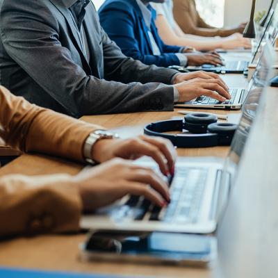 Businesspeople's hands on their laptop keyboards.