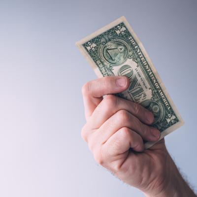 A focused photo of a person holding a one dollar bill.