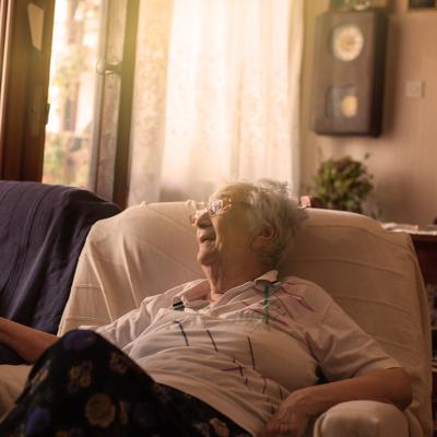 An old woman sitting on a sofa at home.