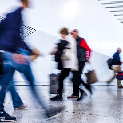 A motion blur shot of passengers walking inside an airport.