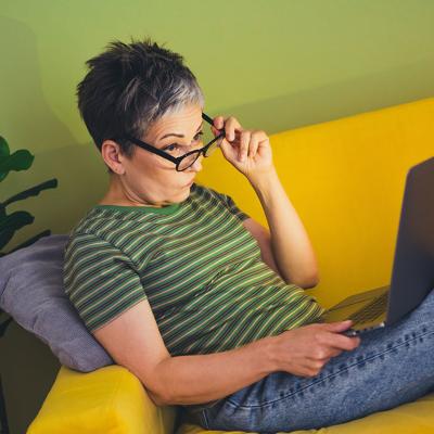 A middle aged woman skeptically browsing the internet at home.