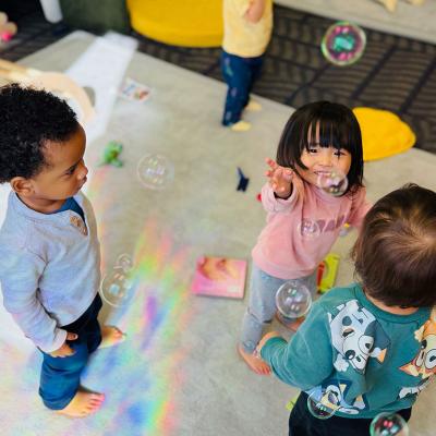 Young children playing with bubbles in day care. In the U.S., families spend between nine percent and 16 percent of their median income on full-day care for just one child.