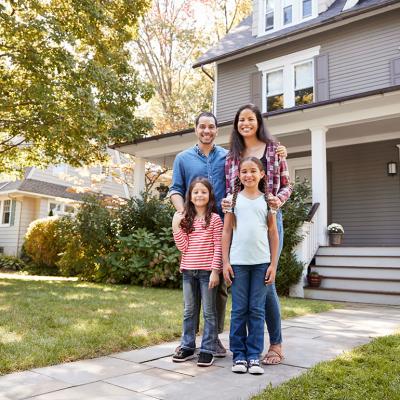 A family of four happily standing in front of their home for a photo.
