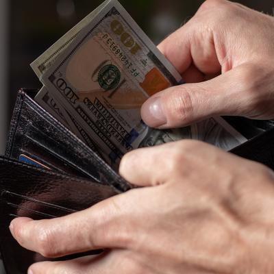 A person taking out dollar bills from a wallet.