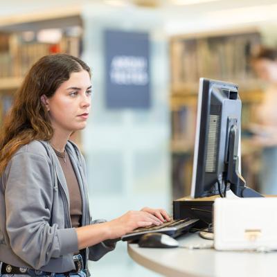 A female student using a computer at a university library.