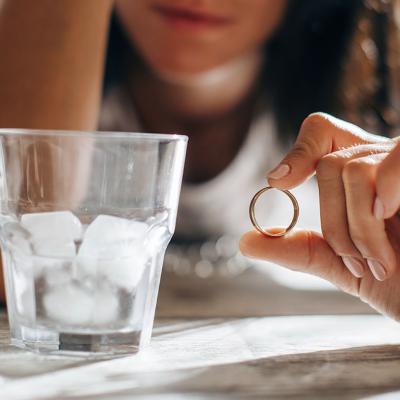 A sad woman holding wedding ring.