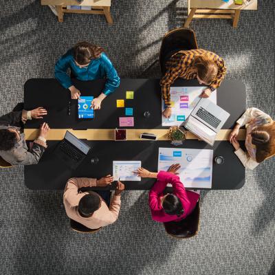 Top view of a team of entrepreneurs seated around a table in a meeting room.