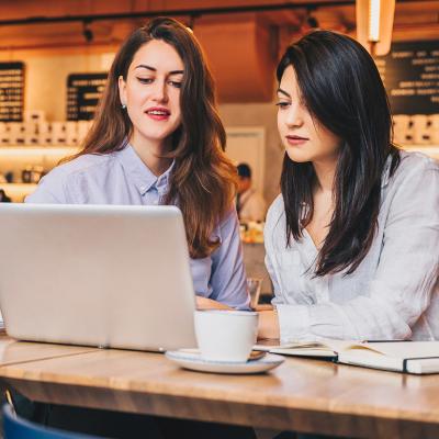 Two businesswomen at a cafe working on a project together.