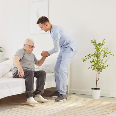 A nurse helping an elderly patient get out of bed in a nursing home. 