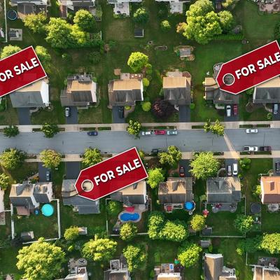 A top aerial view of a neighborhood with some homes marked ‘For Sale.’