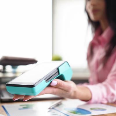 A person holding a banking mobile device in a workplace. 