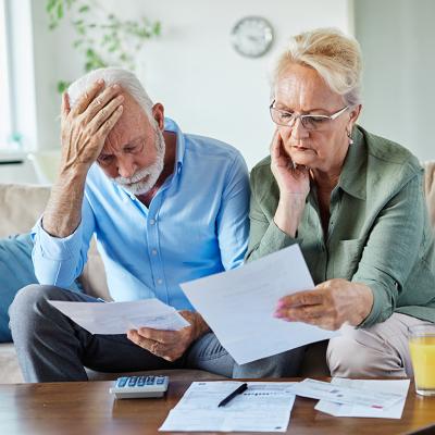 An elderly couple checking bills at home. 