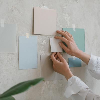Woman hanging paint color mock ups on a wall.