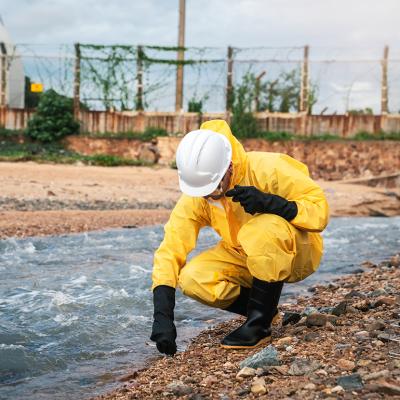 A factory worker in hazmat suit performs environmental inspection.