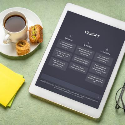 Webpage of ChatGPT on a tablet beside a cup of coffee and sticky notes.