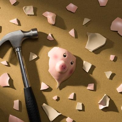 A broken piggy bank and a hammer on the floor.