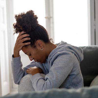 A young black woman experiencing headache at home.