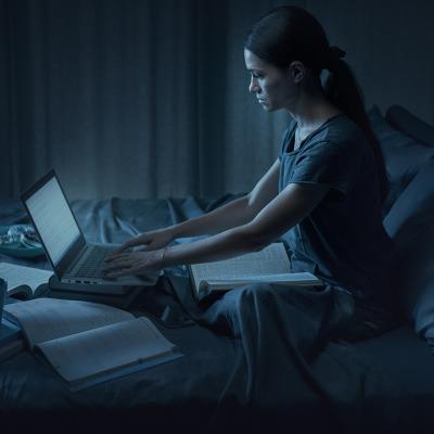 A student pulling an all-nighter for an exam in her bedroom. 
