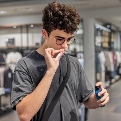 A person smelling a perfume's scent blotter in a store. 