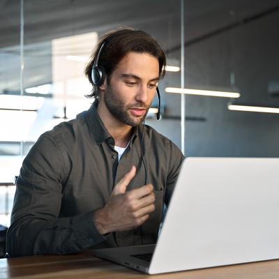 A male customer support service employee in an office working on a call with a client.