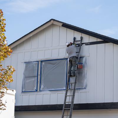 A house painter doing trim work of a house's exterior wall. 