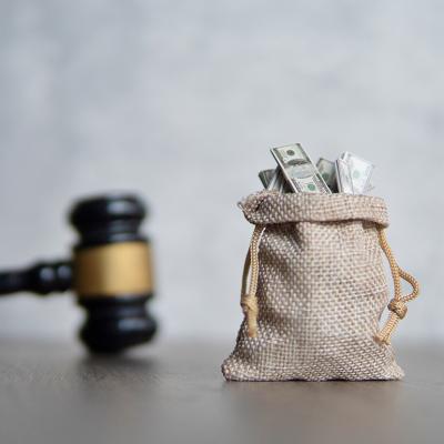 A small bag of money and a judge's gavel as a concept of penalty in lawsuit.
