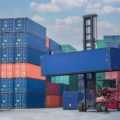 A forklift lifting a container van in a shipping yard.
