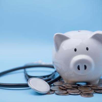 A piggy bank with coins and a stethoscope.