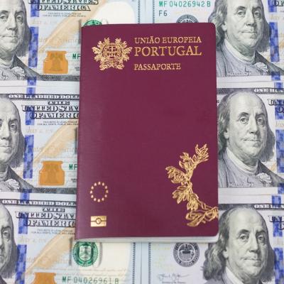 A Portuguese passport on top of one hundred U.S. dollar bills. 