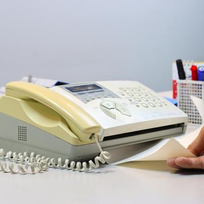 Person feeding a yellowing fax machine paper.