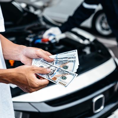 Customer pays with cash to the car mechanic after a service.