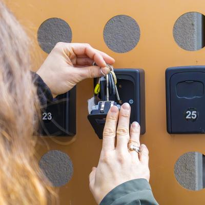 A person putting keys inside an apartment key box.