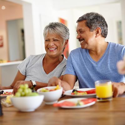 A retired senior couple happily having breakfast at home.
