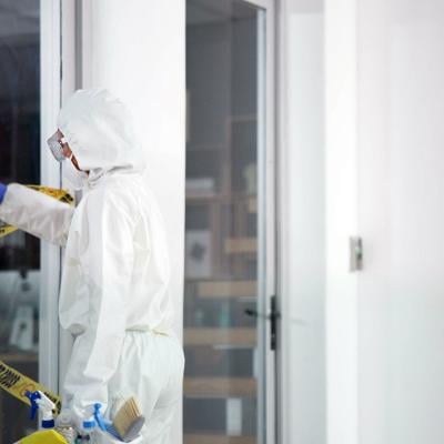 A forensic team removing a barrier tape from a crime scene.