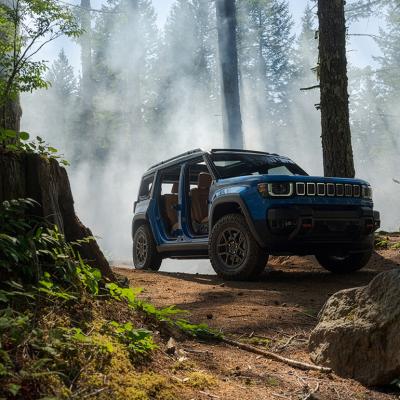 Low angle view of a Blue Jeep Recon Moab parked in a forest with mist rising in the background.