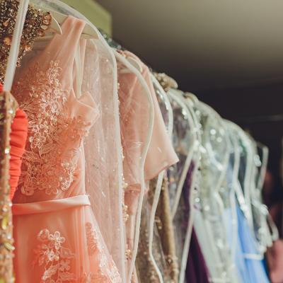 A row of ladies' long gown dresses in a closet.