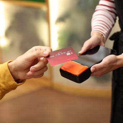 A person paying with a credit card payment machine held by a cafe staff.