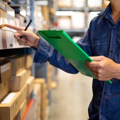 A factory assistant checking stocks for an inventory at a warehouse.