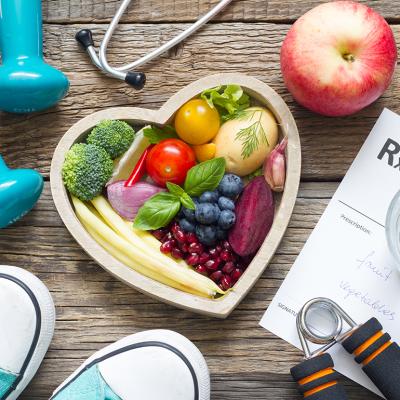 Fruits and vegetables in a heart bowl surrounded by fitness and healthy lifestyle objects.