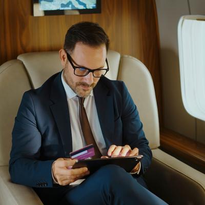 A business executive shopping online while traveling from a private jet's cabin.