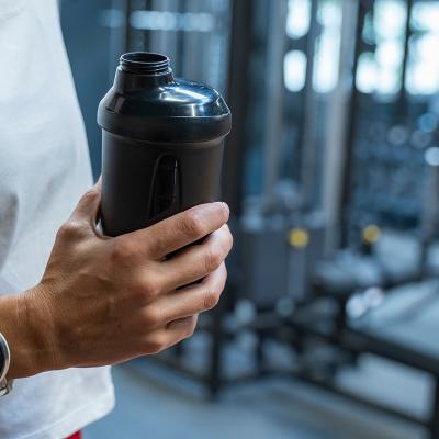 A person holding a water bottle during her workout in a gym. 