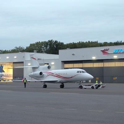 Line technicians working at the Teterboro Airport, operating aircraft towing vehicles and parking airplanes in the hangar.