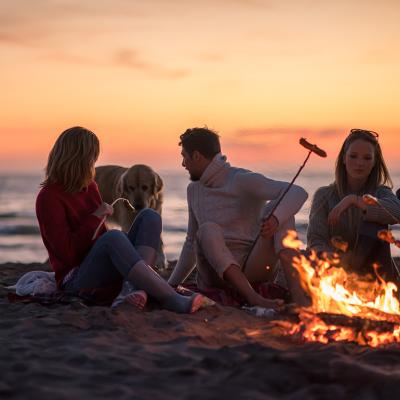 A group of friends sitting around a campfire by the beach.