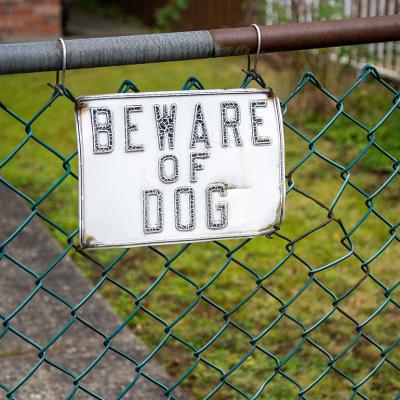 A Beware of Dog sign hung to a house's gate.