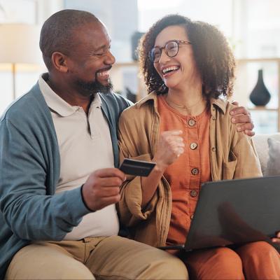 A happy couple at home purchasing online with a credit card.