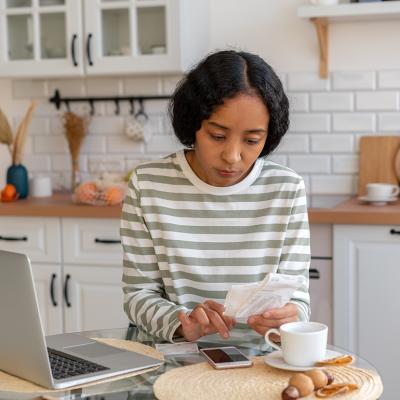 A young woman at home calculating expenses.