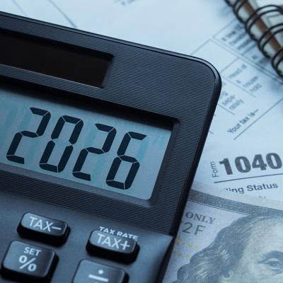 '2026' on a calculator over tax forms.