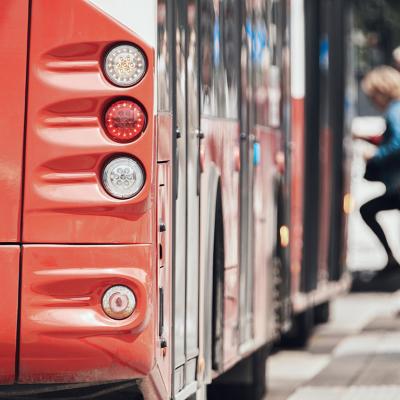 Rear view of a public transport bus at a stop with passengers entering.