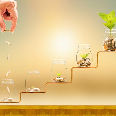 Hand dropping gold coins on jars on a staircase as a concept of financial building.