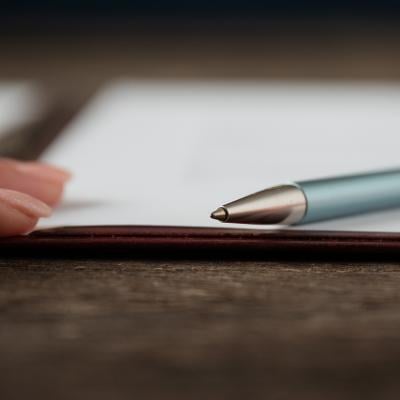 Low angle view of a hand and a pen lying on a document.